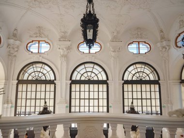 Wien, Austria - July 28, 2023: Impressive interior of hall in Upper Belvedere Palace in Vienna with staircase decorated with white stucco reliefs, sculptures and antique forged lanterns clipart