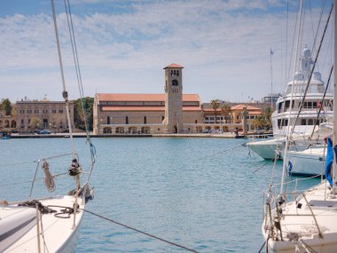 Rhodes, Greece - 16 April 2023: Mandraki harbor on Rhodes Island, famous for its deer statues. The Rhodes Statue stood here in ancient times. Tourists are on the island. clipart