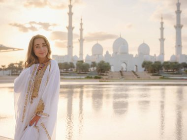 Abu Dabi 'deki Birleşik Arap Emirlikleri' ne git. Beyaz Arap elbiseli kadın Şeyh Zayed Büyük Beyaz Cami 'ye bakıyor. Ünlü Abu Dabi gezisi..