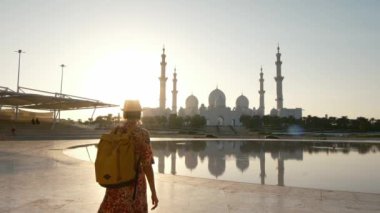 Kadın turist, Abu Dabi 'deki Şeyh Zayed Camii' nin çarpıcı manzarasını izlerken huzurlu bir anın tadını çıkarıyor. Büyük mimari ve huzurlu çevre, Wahat Al Karama parkından manzara