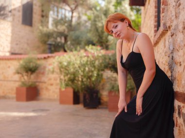 Zarif siyah elbiseli genç bir kadın yaz günü Türkiye 'nin Keleci, Antalya kentinde yürüyor. Kadın gezgin ilginç yerler ve popüler yerler keşfediyor.