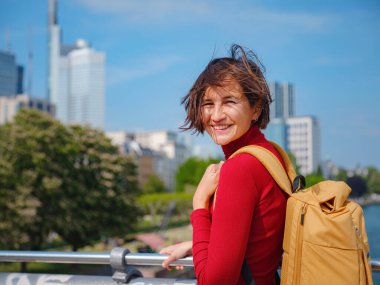 Turist kadın modern Frankfurt 'u keşfediyor, çağdaş mimari, gökdelenler ve kentsel alanlarla hareketli caddelerde yürüyor, modern yan tarafların canlı atmosferinin tadını çıkarıyor..