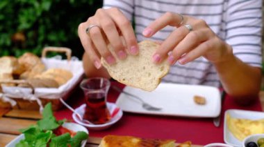 Kadınlar bahçede geleneksel Türk kahvaltısını seviyor. Etrafı yeşilliklerle çevrili bir masada oturuyor. Tabağında taze ekmek, peynir, zeytin, domates, salatalık, yumurta ve bal var. Bir fincan Türk çayı.