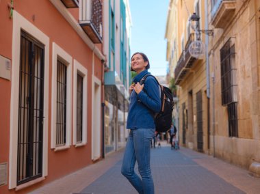İspanya 'nın Alicante eyaletinin büyüleyici dar sokaklarında gezinen, tarihi Akdeniz mimarisi ile çevrili, barışçıl atmosfer ve kültürel ortamın tadını çıkaran genç bir kadın..