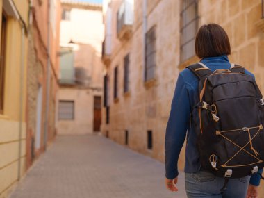 İspanya 'nın Alicante eyaletinin büyüleyici dar sokaklarında gezinen, tarihi Akdeniz mimarisi ile çevrili, barışçıl atmosfer ve kültürel ortamın tadını çıkaran genç bir kadın..