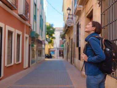 İspanya 'nın Alicante eyaletinin büyüleyici dar sokaklarında gezinen, tarihi Akdeniz mimarisi ile çevrili, barışçıl atmosfer ve kültürel ortamın tadını çıkaran genç bir kadın..