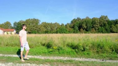 Tarlalar ve ormanlarla çevrili kırsal toprak yolda yürüyen bir adam kırsal hayatın huzurlu ve kırsal atmosferini yakalıyor. Yalnızlığı ve doğayı vurgulayan basit, sessiz bir sahne..