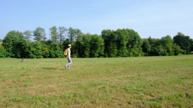 Kırsal alanlarda yürüyüş yapan bir kadın, açık araziler, temiz hava ve huzurlu kırsal manzarayla çevrili. Açık havanın doğal güzelliğini ve sükunetini seviyor..