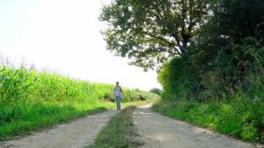 Kırsal alanlarda yürüyüş yapan bir kadın, açık araziler, temiz hava ve huzurlu kırsal manzarayla çevrili. Açık havanın doğal güzelliğini ve sükunetini seviyor..