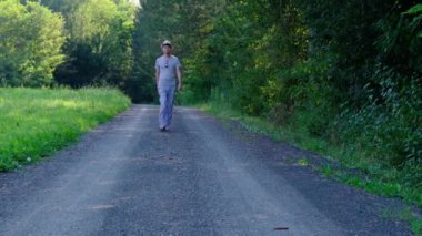 Tarlalar ve ormanlarla çevrili kırsal toprak yolda yürüyen bir adam kırsal hayatın huzurlu ve kırsal atmosferini yakalıyor. Yalnızlığı ve doğayı vurgulayan basit, sessiz bir sahne..