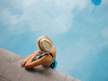 Kuala Lumpur Oteli 'nde havuz başında dinlenen Asyalı genç bir kadın. Etrafı gökdelenlerle çevrili, hareketli şehir ortamında boş vakitlerin tadını çıkarıyor..