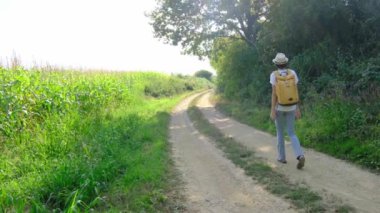 Kırsal alanlarda yürüyüş yapan bir kadın, açık araziler, temiz hava ve huzurlu kırsal manzarayla çevrili. Açık havanın doğal güzelliğini ve sükunetini seviyor..