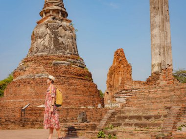 Tayland 'ın Ayutthaya kentinde tarihi parkı keşfetmek için giyinmiş genç bir bayan turist. Antik tapınaklar ve heykellerle çevrili, huzurlu bir atmosfer ve zengin kültürel mirasın tadını çıkarıyor..