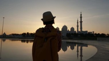 Kadın turist, Abu Dabi 'deki Şeyh Zayed Camii' nin çarpıcı manzarasına hayran kalarak huzurlu bir anın tadını çıkarıyor. Wahat Al Karama 'nın büyük mimarisi ve barışçıl çevre manzarası