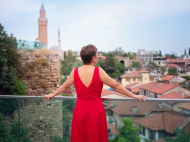 Sıcak yaz akşamları Antalya 'nın dar sokaklarında kırmızı elbiseli bir kadın yürüyor. Tarihsel atmosfer ve Akdeniz cazibesi barışçıl seyahat deneyimleri yaratır. Kalechi manzarası
