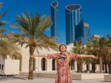 Young woman exploring Qasr Al Hosn Park in Abu Dhabi. Surrounded by lush greenery and historical landmarks, she enjoys the serene atmosphere and Emirati heritage in heart of city. clipart