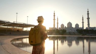 Kadın turist, Abu Dabi 'deki Şeyh Zayed Camii' nin çarpıcı manzarasını izlerken huzurlu bir anın tadını çıkarıyor. Büyük mimari ve huzurlu çevre, Wahat Al Karama parkından manzara