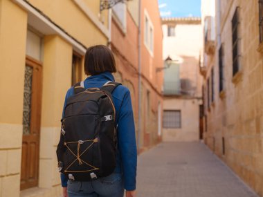 İspanya 'nın Alicante eyaletinin büyüleyici dar sokaklarında gezinen, tarihi Akdeniz mimarisi ile çevrili, barışçıl atmosfer ve kültürel ortamın tadını çıkaran genç bir kadın..