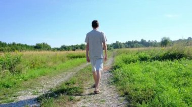 Tarlalar ve ormanlarla çevrili kırsal toprak yolda yürüyen bir adam kırsal hayatın huzurlu ve kırsal atmosferini yakalıyor. Yalnızlığı ve doğayı vurgulayan basit, sessiz bir sahne..