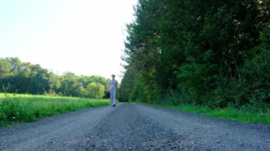 Tarlalar ve ormanlarla çevrili kırsal toprak yolda yürüyen bir adam kırsal hayatın huzurlu ve kırsal atmosferini yakalıyor. Yalnızlığı ve doğayı vurgulayan basit, sessiz bir sahne..