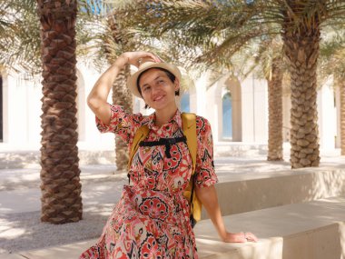 Abu Dabi 'de Qasr Al Hosn Parkı' nı keşfeden genç bir kadın. Yeşillik ve tarihi simgelerle çevrelenmiş, kentin kalbindeki sakin atmosfer ve Emirati mirasının tadını çıkarıyor..