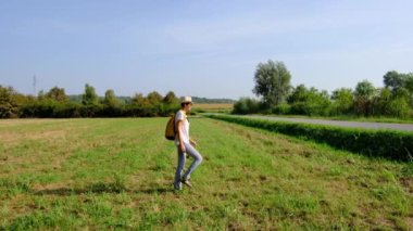 Kırsal alanlarda yürüyüş yapan bir kadın, açık araziler, temiz hava ve huzurlu kırsal manzarayla çevrili. Açık havanın doğal güzelliğini ve sükunetini seviyor..