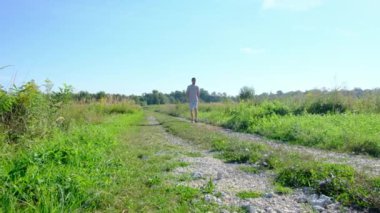 Tarlalar ve ormanlarla çevrili kırsal toprak yolda yürüyen bir adam kırsal hayatın huzurlu ve kırsal atmosferini yakalıyor. Yalnızlığı ve doğayı vurgulayan basit, sessiz bir sahne..