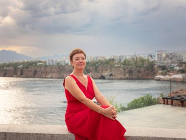 Sıcak yaz akşamları Antalya 'nın dar sokaklarında kırmızı elbiseli bir kadın yürüyor. Tarihsel atmosfer ve Akdeniz cazibesi barışçıl seyahat deneyimleri yaratır. Eski liman ve kentte görünüm