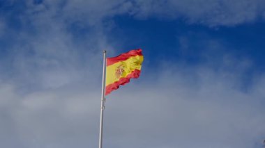 İspanyol bayrağı zarif bir şekilde mavi gökyüzüne doğru dalgalanıyor. Spains kültürel kimliğinin özünü yakalayan ulusal gurur, birlik ve mirasın güçlü bir sembolü.