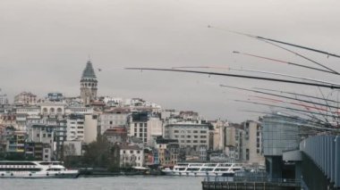 İstanbul, Türkiye - 3 Aralık 2023. Galata Köprüsü 'nde elinde olta olan balıkçılar Galata Kulesi manzaralı. Tarihi ve modern şehrin arka planında oltaları olan balıkçıların manzara görüntüsü.
