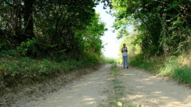 Kırsal alanlarda yürüyüş yapan bir kadın, açık araziler, temiz hava ve huzurlu kırsal manzarayla çevrili. Açık havanın doğal güzelliğini ve sükunetini seviyor..