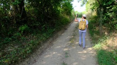 Kırsal alanlarda yürüyüş yapan bir kadın, açık araziler, temiz hava ve huzurlu kırsal manzarayla çevrili. Açık havanın doğal güzelliğini ve sükunetini seviyor..