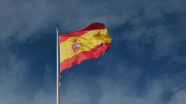 İspanyol bayrağı zarif bir şekilde mavi gökyüzüne doğru dalgalanıyor. Spains kültürel kimliğinin özünü yakalayan ulusal gurur, birlik ve mirasın güçlü bir sembolü.
