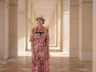 Young woman exploring Qasr Al Hosn Park in Abu Dhabi. Surrounded by lush greenery and historical landmarks, she enjoys the serene atmosphere and Emirati heritage in heart of city. clipart