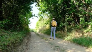 Kırsal alanlarda yürüyüş yapan bir kadın, açık araziler, temiz hava ve huzurlu kırsal manzarayla çevrili. Açık havanın doğal güzelliğini ve sükunetini seviyor..