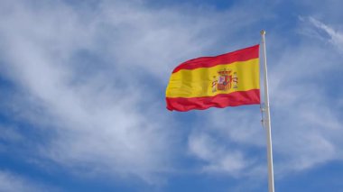 İspanyol bayrağı zarif bir şekilde mavi gökyüzüne doğru dalgalanıyor. Spains kültürel kimliğinin özünü yakalayan ulusal gurur, birlik ve mirasın güçlü bir sembolü.