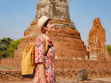 Tayland 'ın Ayutthaya kentinde tarihi parkı keşfetmek için giyinmiş genç bir bayan turist. Antik tapınaklar ve heykellerle çevrili, huzurlu bir atmosfer ve zengin kültürel mirasın tadını çıkarıyor..