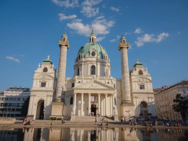 Viyana, Avusturya - 31 Temmuz 2023: Karlsplatz Meydanı 'ndaki Karlskirche Kilisesi gün batımında. Bir Avrupa ülkesinin Viyana başkenti Avusturya. Yaz mimarisi ve kültüründe Viyana 'yı keşfetmek,