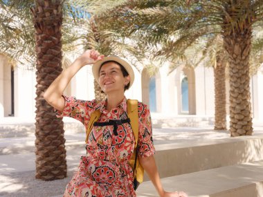 Abu Dabi 'de Qasr Al Hosn Parkı' nı keşfeden genç bir kadın. Yeşillik ve tarihi simgelerle çevrelenmiş, kentin kalbindeki sakin atmosfer ve Emirati mirasının tadını çıkarıyor..