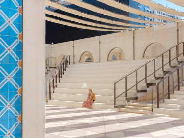 Abu Dabi 'de Qasr Al Hosn Parkı' nı keşfeden genç bir kadın. Yeşillik ve tarihi simgelerle çevrelenmiş, kentin kalbindeki sakin atmosfer ve Emirati mirasının tadını çıkarıyor..