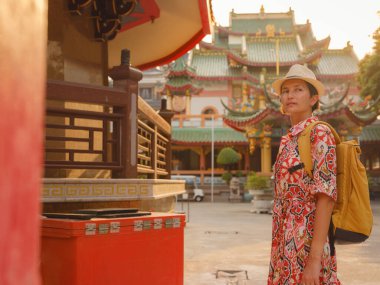 Bangkok 'taki Budist Tapınakları' nın yakınlarındaki Renkli Sokakları Keşfeden Kadın. Bangkok 'un canlı sokaklarında yürüyen genç bir gezgin, karmaşık tapınak detaylarına ve canlı çevresine hayran...