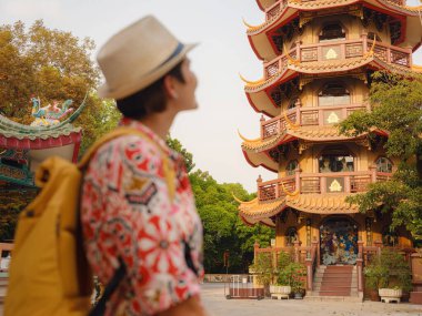 Bangkok 'taki Budist Tapınakları' nın yakınlarındaki Renkli Sokakları Keşfeden Kadın. Bangkok 'un canlı sokaklarında yürüyen genç bir gezgin, karmaşık tapınak detaylarına ve canlı çevresine hayran...