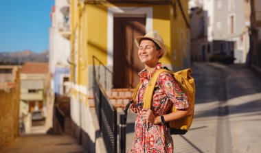 Avrupa 'da turizm. Palmiye ağaçları ve plajlarla dolu renkli İspanyol köyünü ziyaret eden mutlu gezgin kız Villajoyosa, Alicante, İspanya.