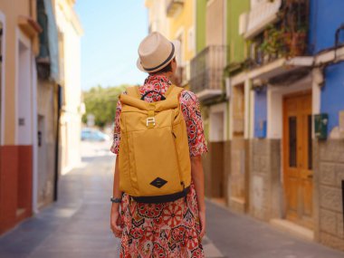 Avrupa 'da turizm. Palmiye ağaçları ve plajlarla dolu renkli İspanyol köyünü ziyaret eden mutlu gezgin kız Villajoyosa, Alicante, İspanya. arka plan