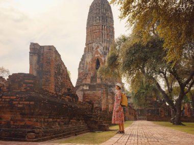 Tayland 'ın Ayutthaya kentinde tarihi parkı keşfetmek için giyinmiş genç bir bayan turist. Antik tapınaklar ve heykellerle çevrili, huzurlu bir atmosfer ve zengin kültürel mirasın tadını çıkarıyor..