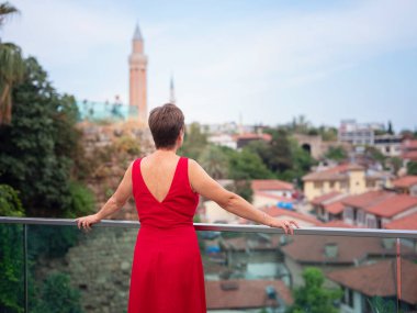 Sıcak yaz akşamları Antalya 'nın dar sokaklarında kırmızı elbiseli bir kadın yürüyor. Tarihsel atmosfer ve Akdeniz cazibesi barışçıl seyahat deneyimleri yaratır. Kalechi manzarası