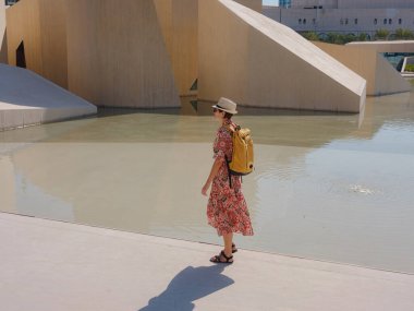 Abu Dabi 'de Qasr Al Hosn Parkı' nı keşfeden genç bir kadın. Yeşillik ve tarihi simgelerle çevrelenmiş, kentin kalbindeki sakin atmosfer ve Emirati mirasının tadını çıkarıyor..