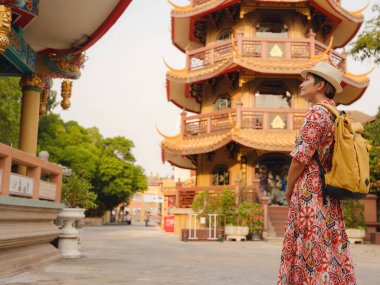 Bangkok 'taki Budist Tapınakları' nın yakınlarındaki Renkli Sokakları Keşfeden Kadın. Bangkok 'un canlı sokaklarında yürüyen genç bir gezgin, karmaşık tapınak detaylarına ve canlı çevresine hayran...