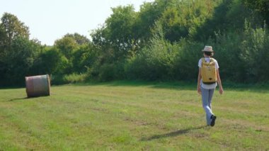Kırsal alanlarda yürüyüş yapan bir kadın, açık araziler, temiz hava ve huzurlu kırsal manzarayla çevrili. Açık havanın doğal güzelliğini ve sükunetini seviyor..