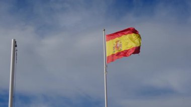 İspanyol bayrağı zarif bir şekilde mavi gökyüzüne doğru dalgalanıyor. Spains kültürel kimliğinin özünü yakalayan ulusal gurur, birlik ve mirasın güçlü bir sembolü.